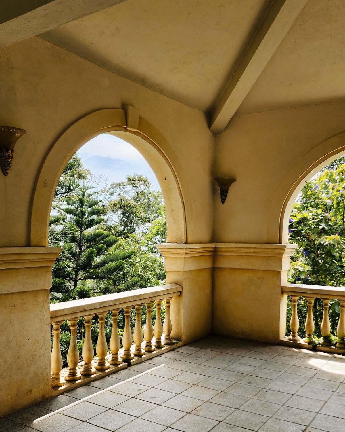 Sunlit terrace with stone arches, balustrade and stone tile floor