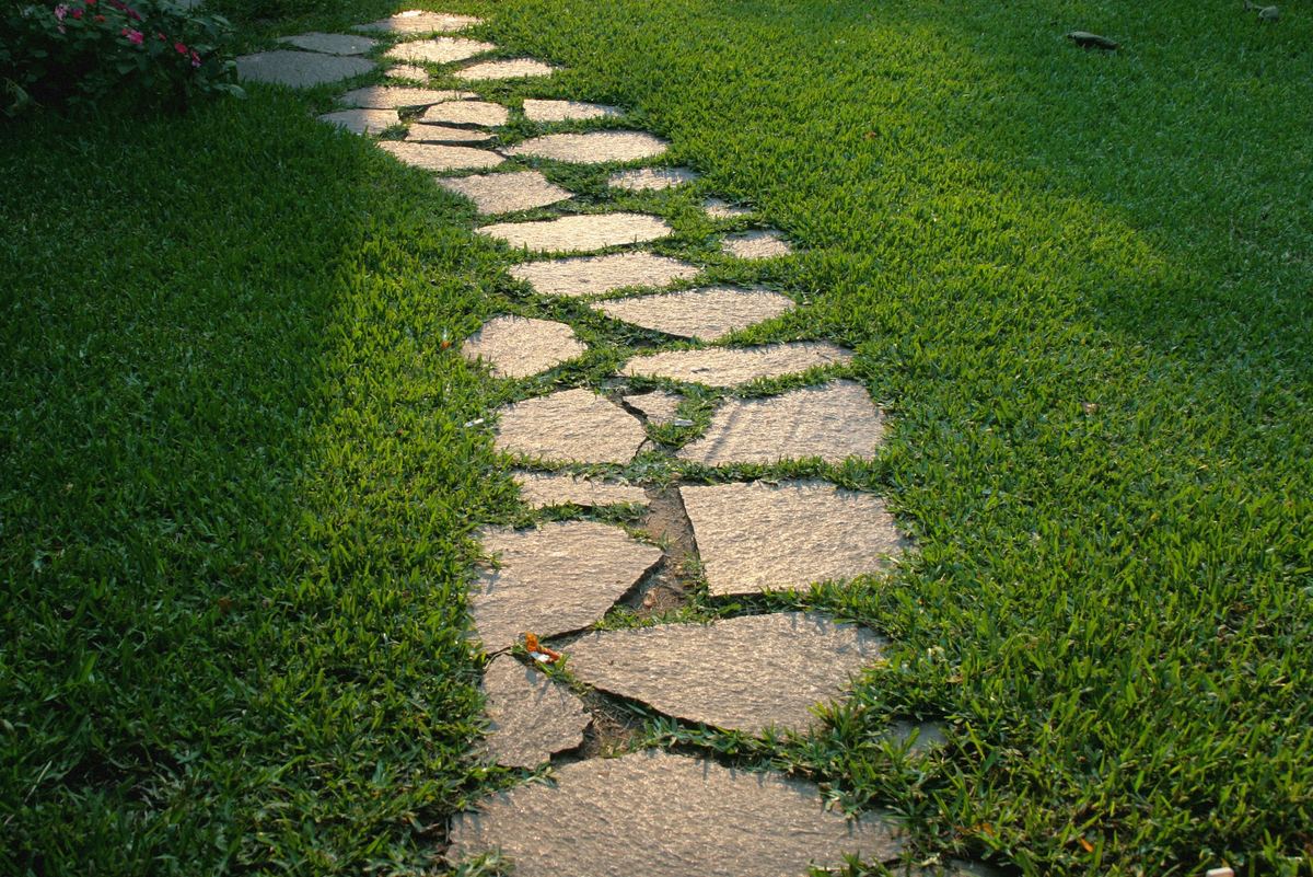 Irregular flagstone stepping-stone path through a green lawn at sunset